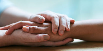 Shot of two people holding hands in comfort